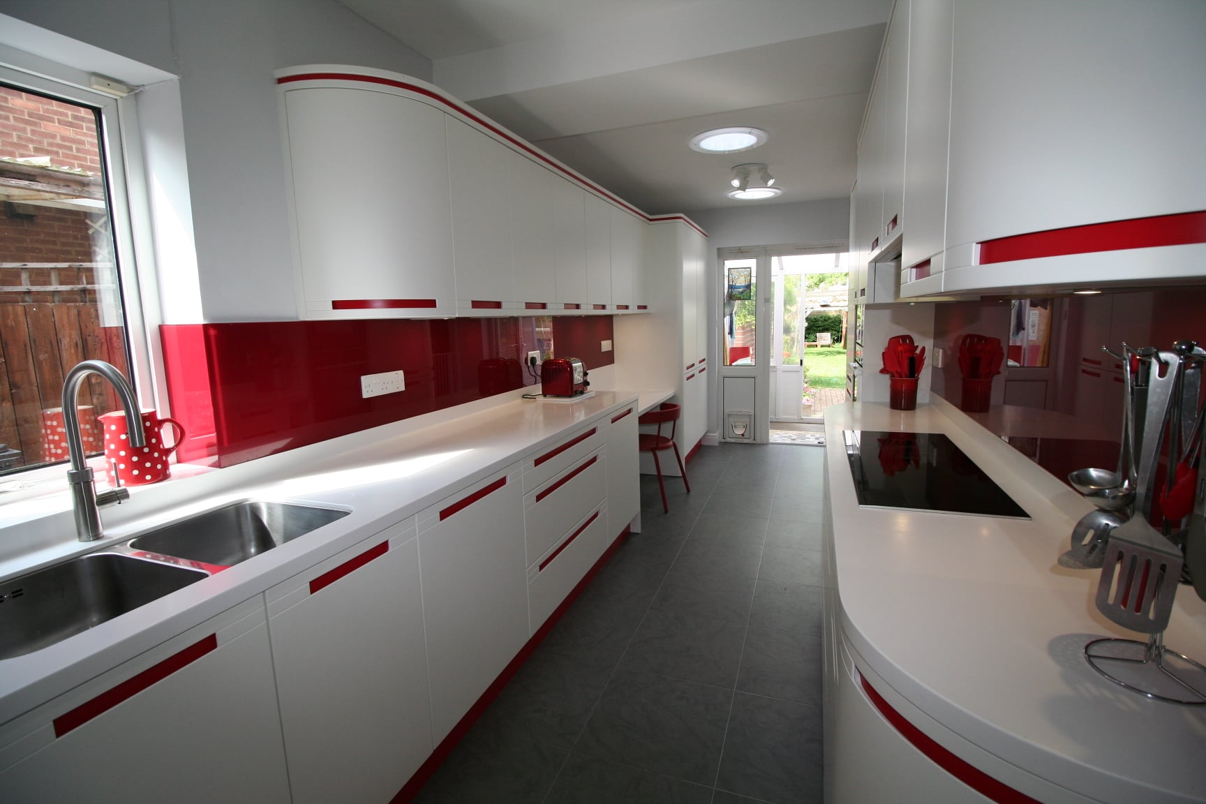Red stripes and curves, 1950s futurism — a Stoneham kitchen by Kitchensmiths, with corian worktops (photograph 2 of 3)