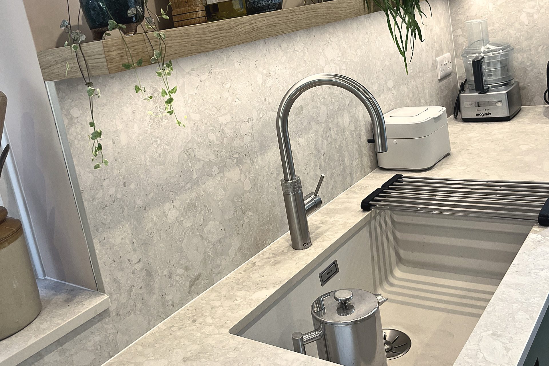Pull-out brushed steel tap over inset sink in pale quartz worktop with stone splashback