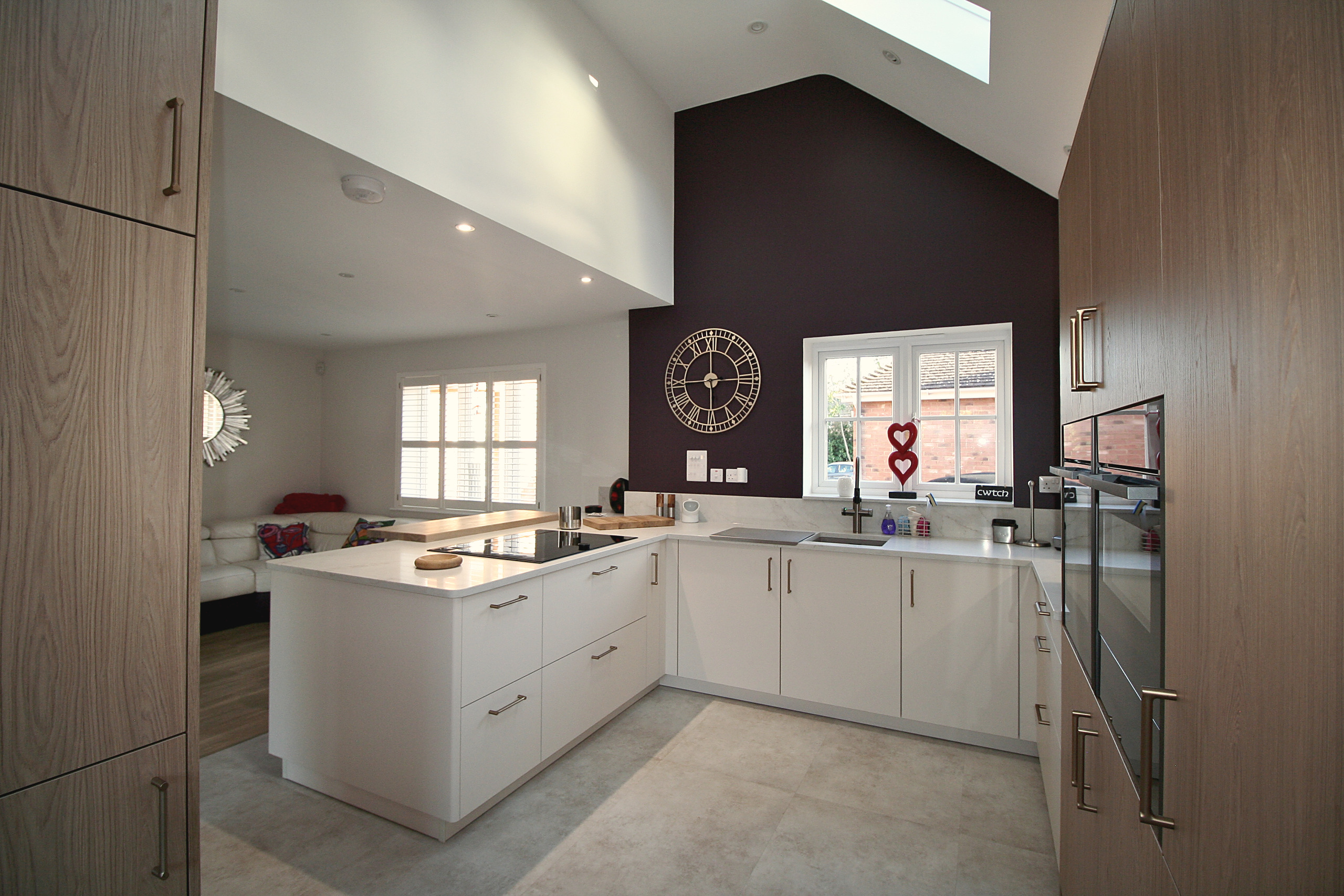 Cashmere kitchen with quartz worktops, black tap and oak tall units, open to a sitting area