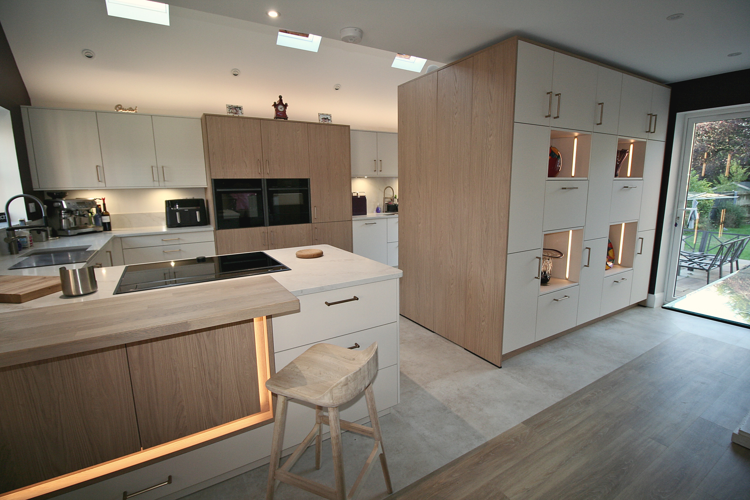 Open plan kitchen with oak and cashmere units, induction hob, rooflights and doors to the garden