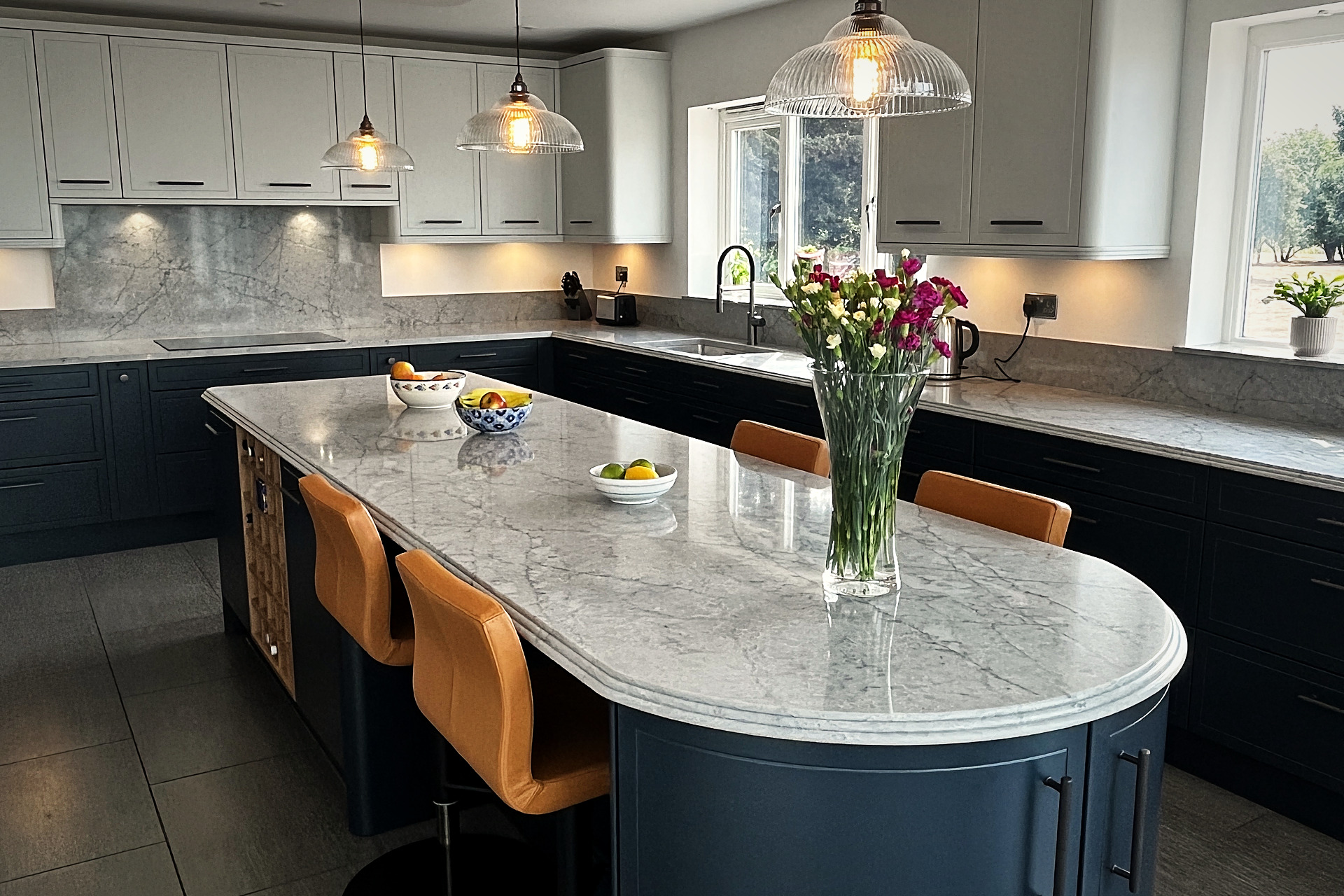 Curved island in Railings blue with Cristallo Platino quartz top and glass ribbed pendant lights above