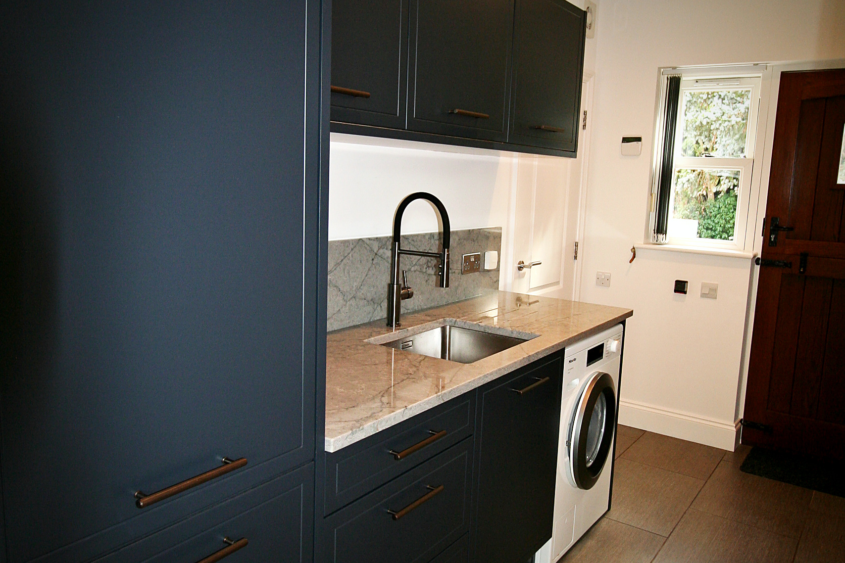 Railings painted utility cabinetry with fluted bronze handles, quartz worktop and integrated washing machine