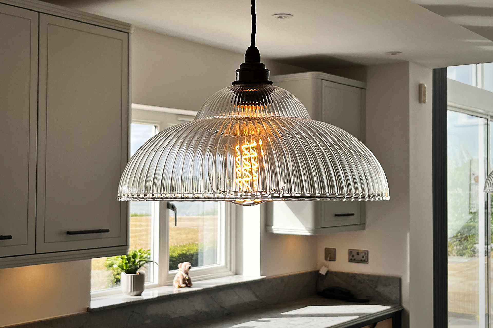 Fritz Fryer ribbed glass pendant light over a Cristallo Platino quartz worktop with fluted bronze handles